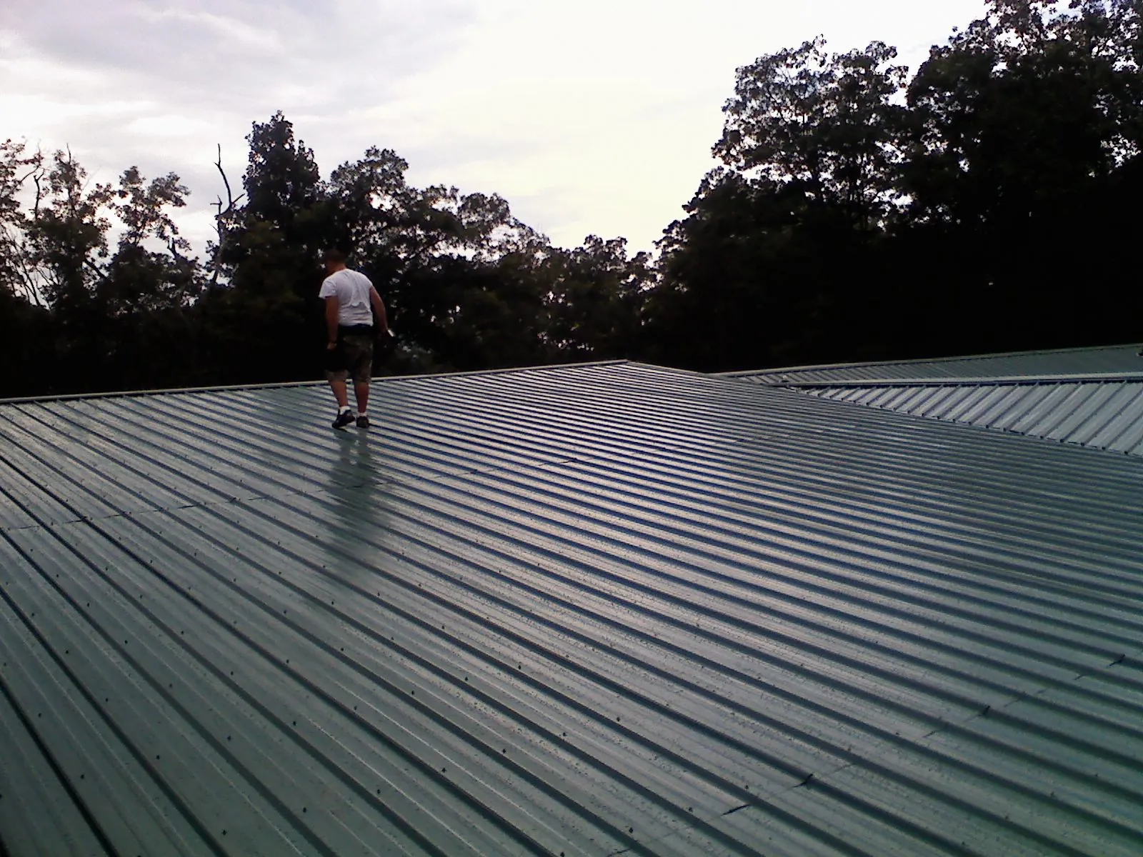 Roofer walking a wide expanse of new green metal roofing in Wishram