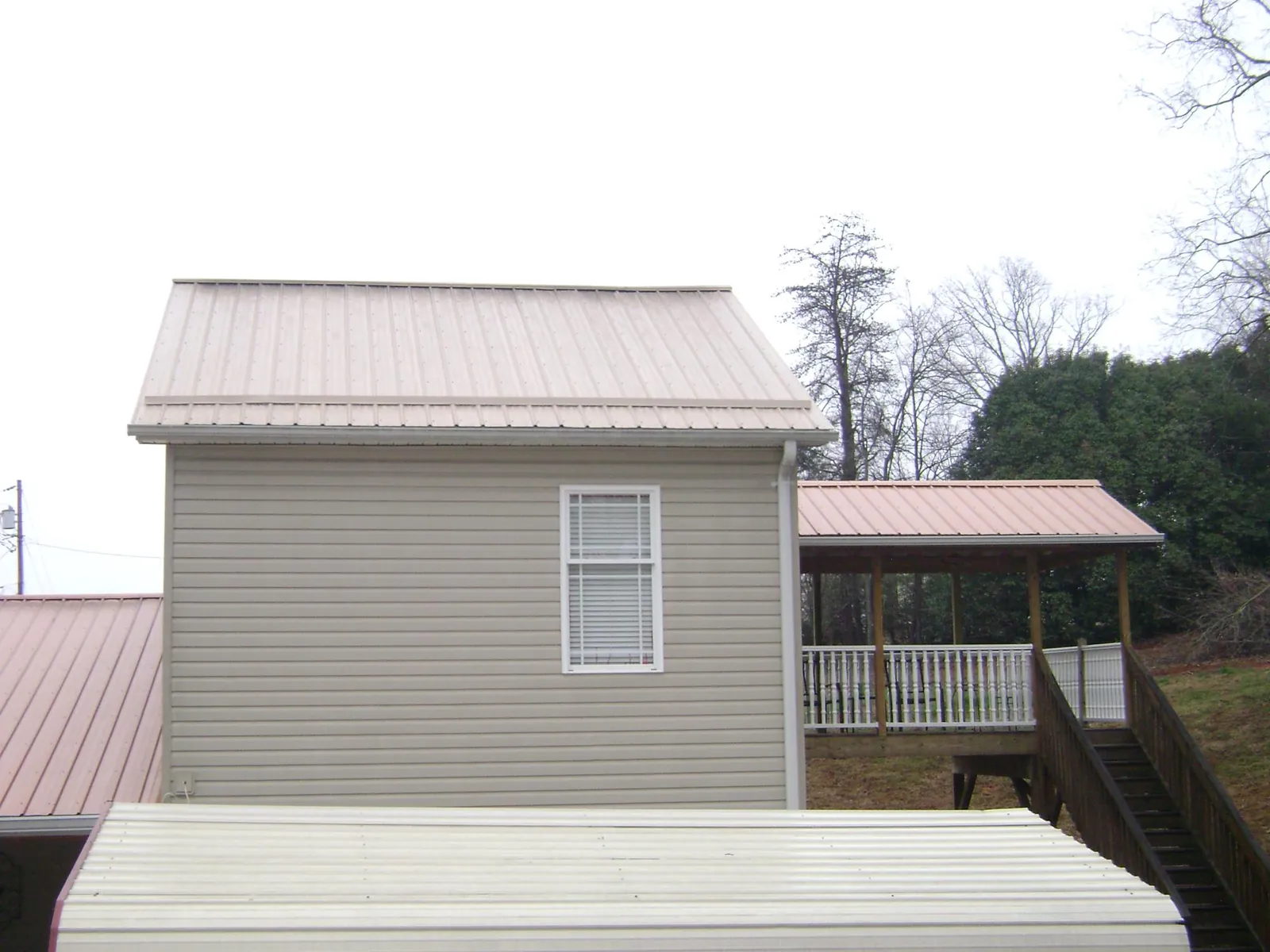 Tan metal roofs on a two story addition and attached porch, from a Roof Replacement job in Wishram