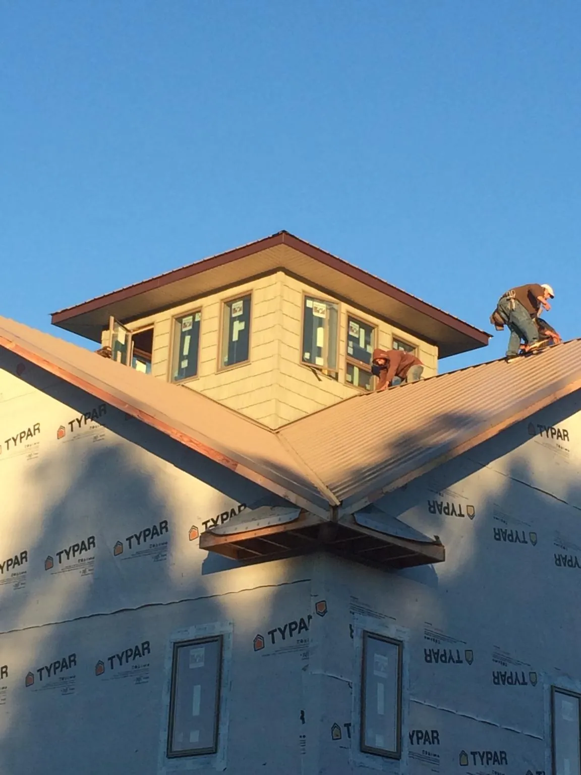 Roofers working around a rooftop cupola on a new metal roof at sunset — Roof Waterproofing in Wishram by Roofing Brothers